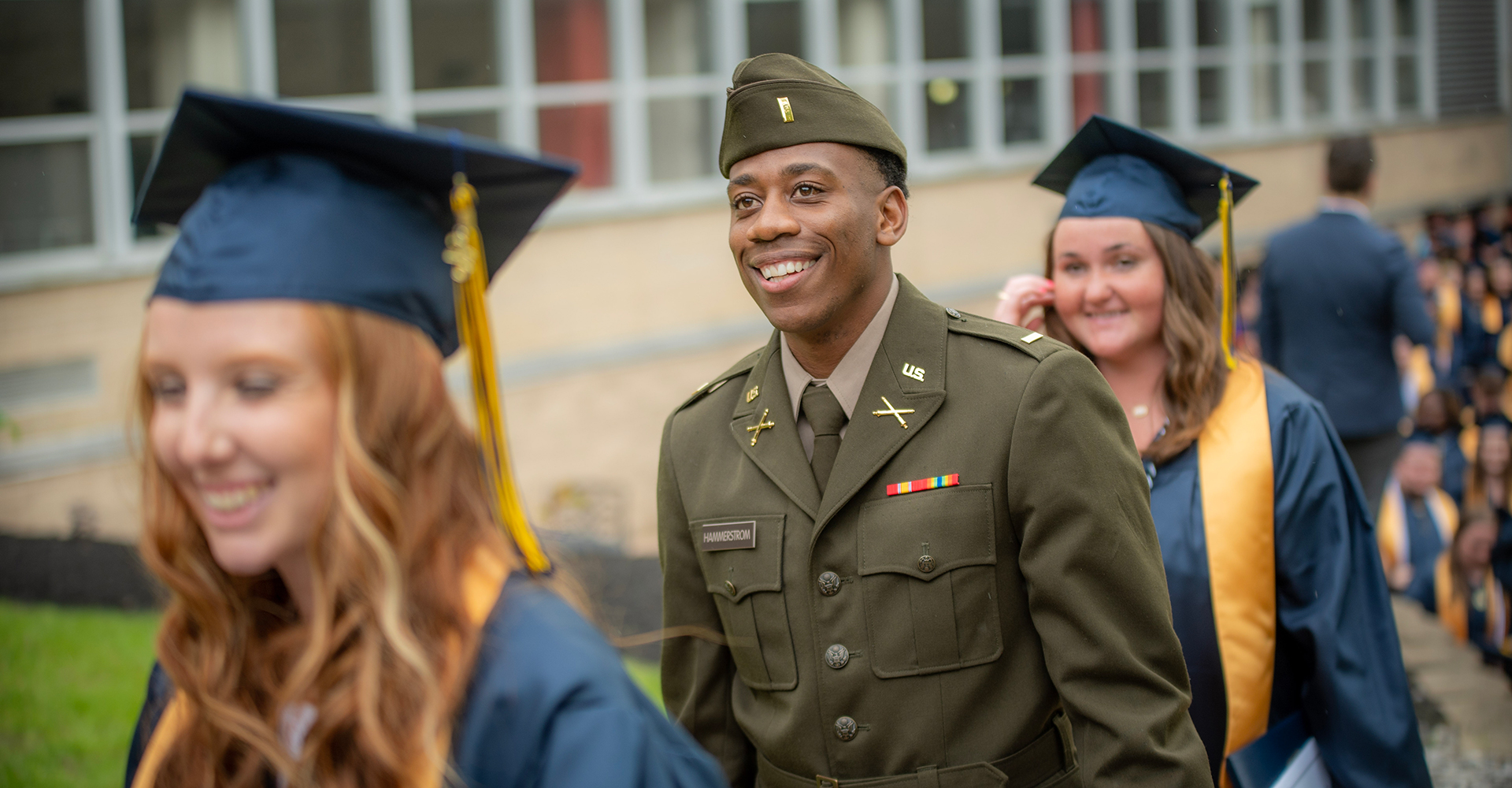 military affiliated graduate walking and smiling during commencement