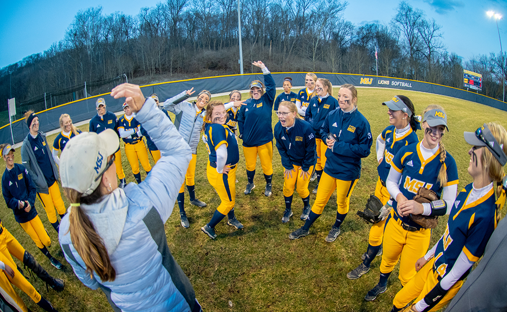 softball team in huddle with coach