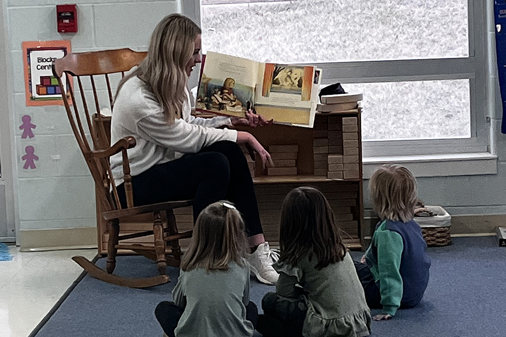 MSJ Childcare assistant reading to young children in Lab School.