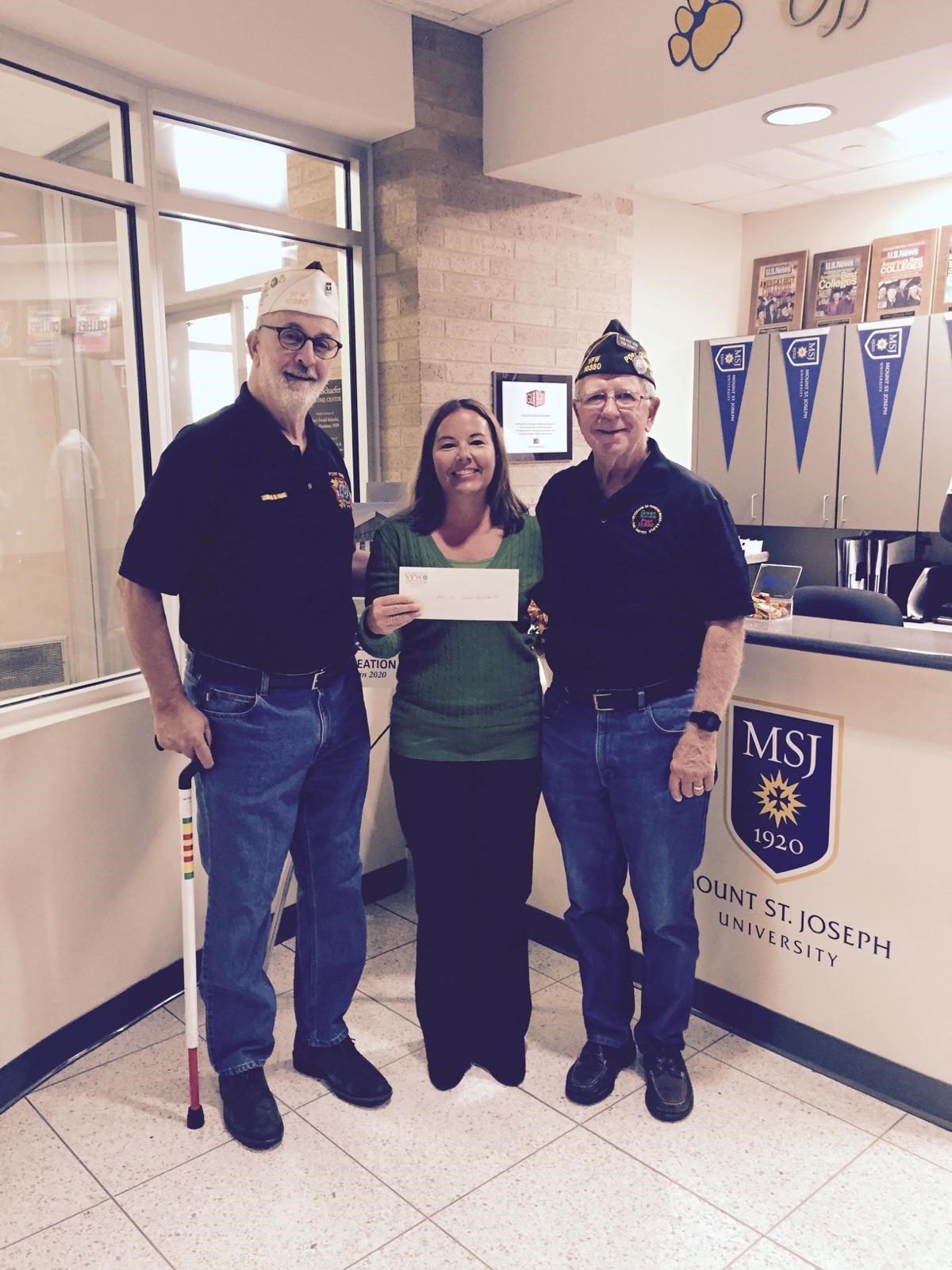 staff member and two veterans holding a donation