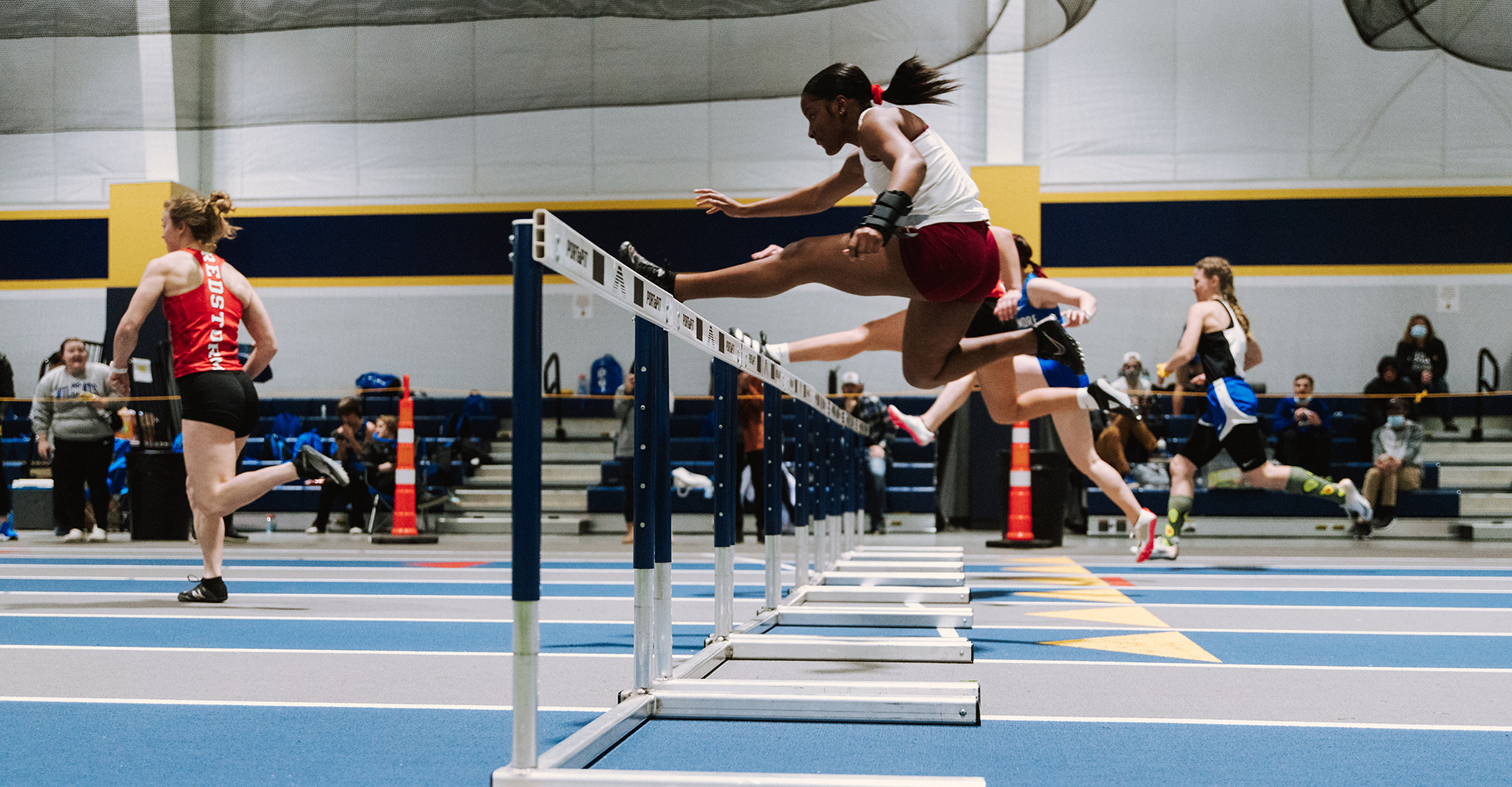 girls running track jumping hurdles