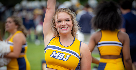 Mount St. Joseph University cheerleader raising arm with pom pom.