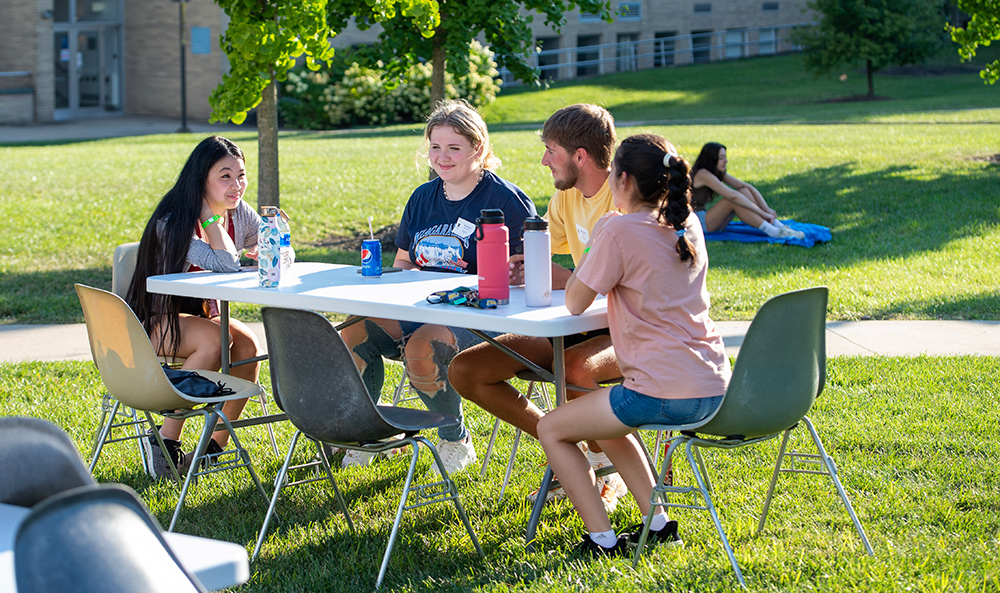 students sitting at table in quad